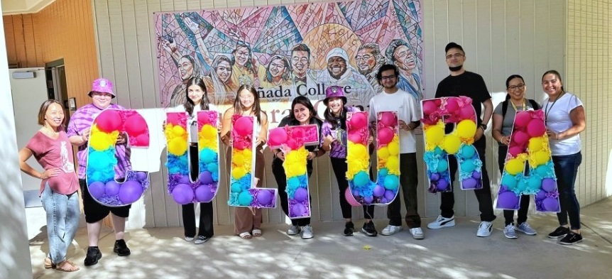 Students and staff stand in front of the new campus mural during the ribbon cutting ceremony