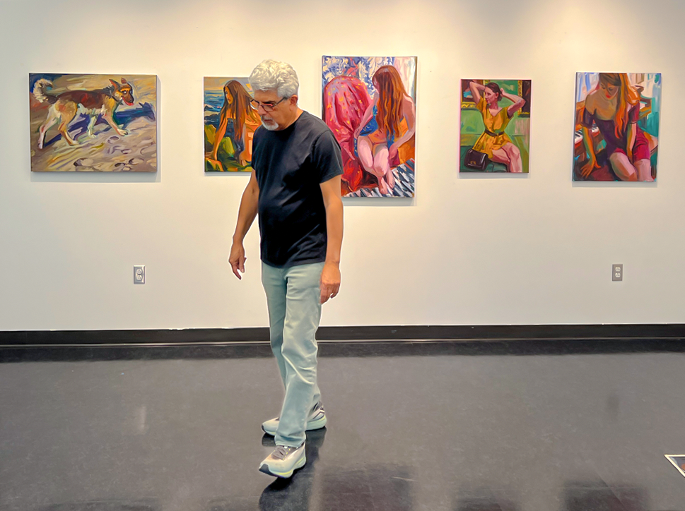 Bill Morales walk through the Cañada College gallery with his paintings on the wall.