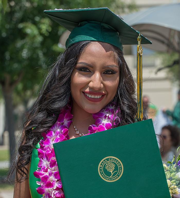 Photo of a Cañada College Graduate wearing a green regalia.