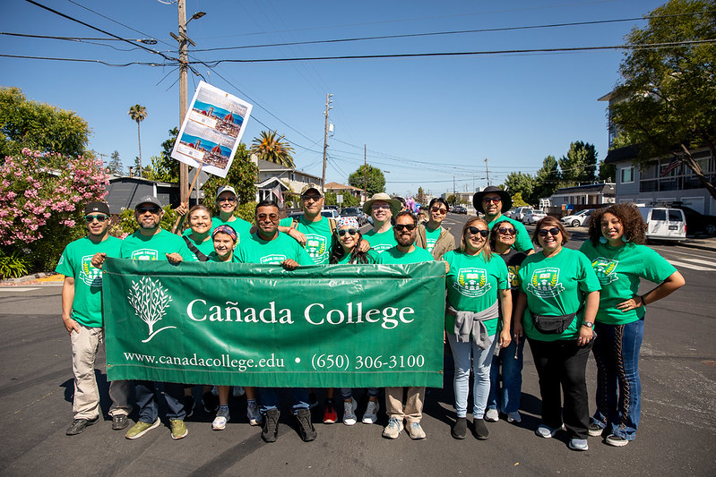 college staff in the community pose for group photo while wearing Cañada thshirts and banner