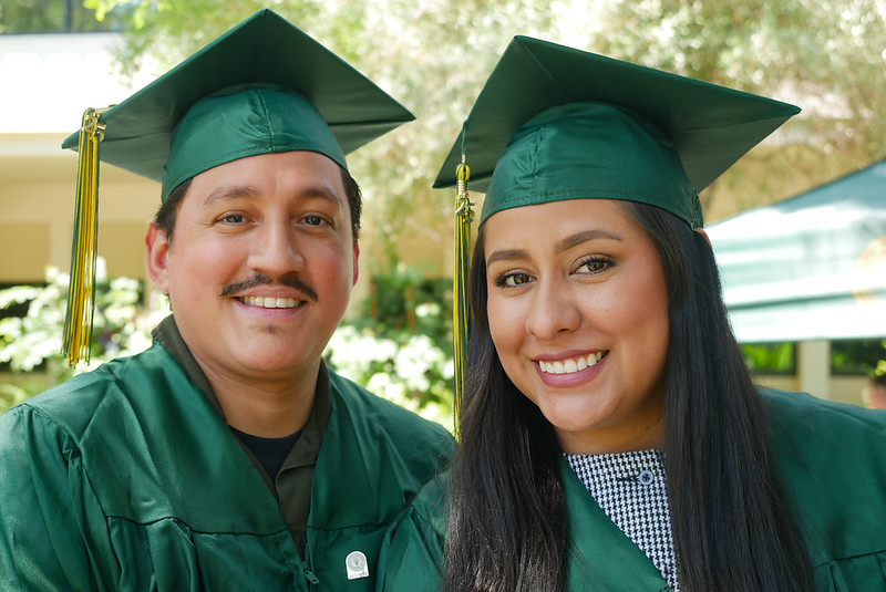 Two adult graduates with cap and gown