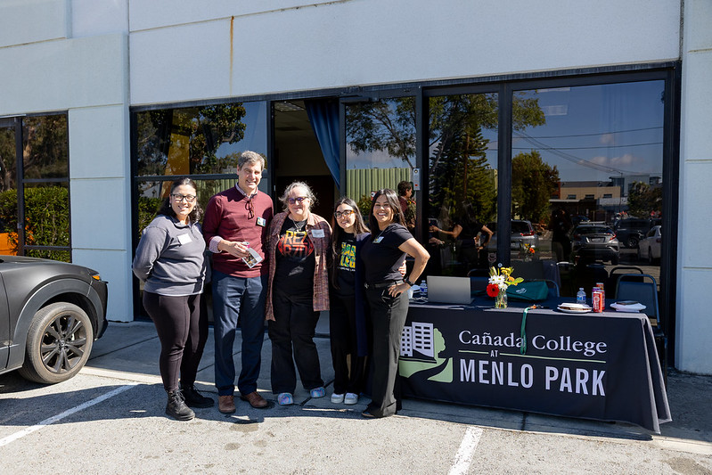 Staff pose and smile while standing outside entrance of Menlo Park site