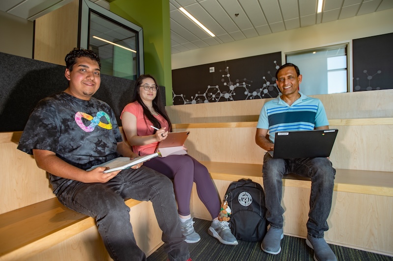 Three students sitting in a lounge area inside the Science and Technology Building