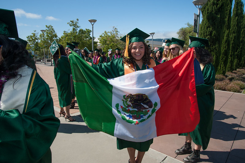 Graduate holding Mexican flag at commencement