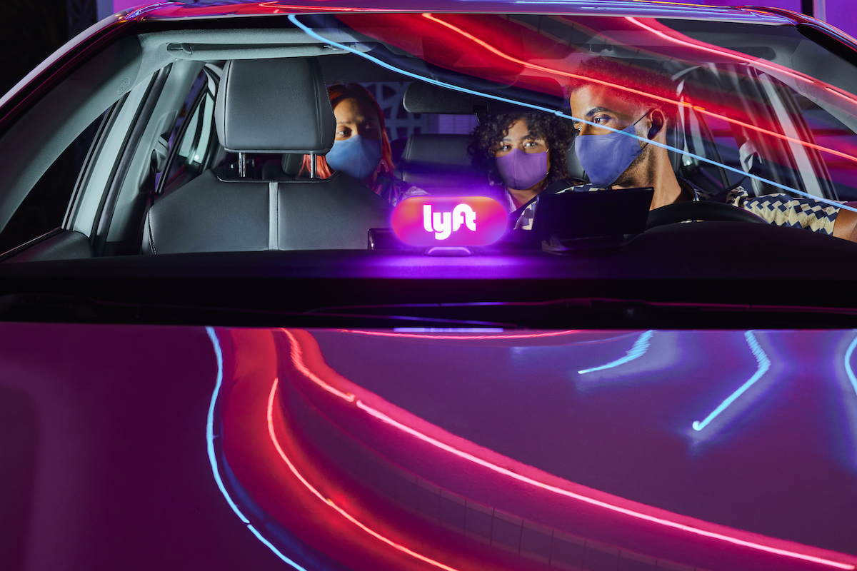 Photo of Lyft driver and passengers wearing a mask inside a car.