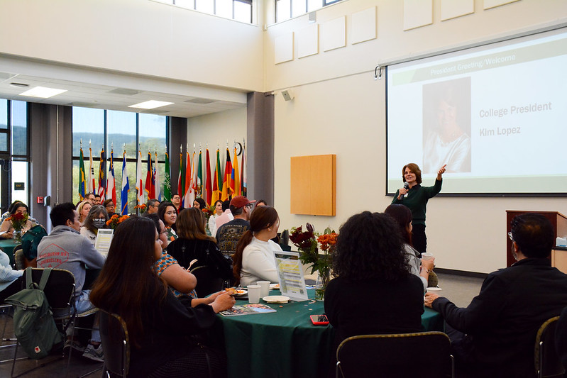 President Kim Lopez delivering a speech to the campus community while holding a microphone