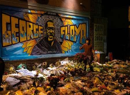 Volunteers in Minneapolis help tidy the site of a memorial for George Floyd, featuring a mural created by three artists. 